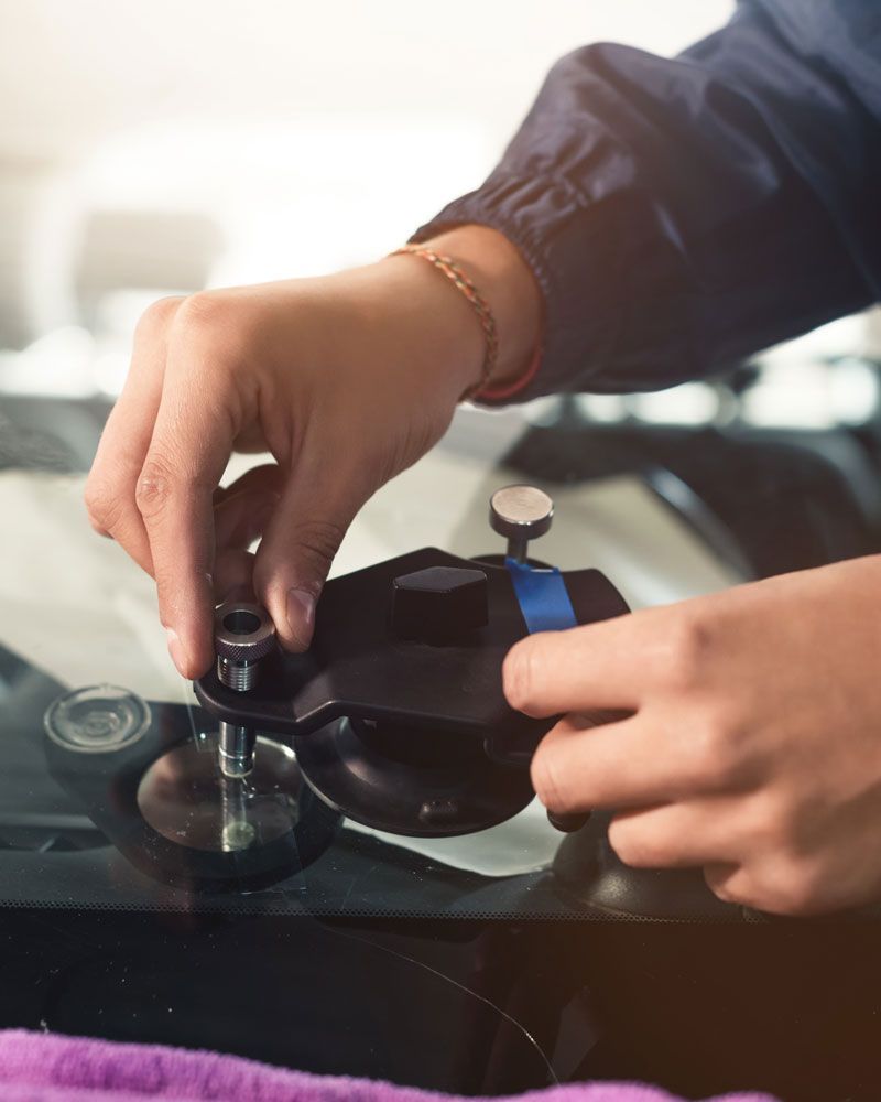 Technician setting a resin injection bridge over a windshield rock chip